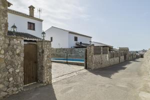 a stone building with a gate and a swimming pool at Casa Carmelo 2 familias o parejas in Conil de la Frontera