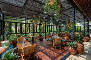 a restaurant with tables and chairs and plants at Ramayana Suites and Resort in Kuta