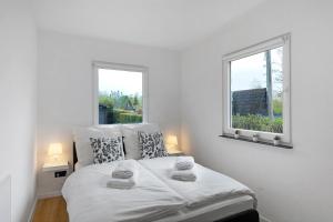 a white bedroom with a bed with two windows at Sauerland Oase in Meschede