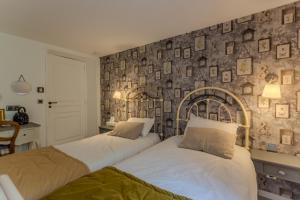 two beds in a bedroom with a wall with pictures at Maison Loustalet in Arzacq-Arraziguet