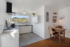 a kitchen with a table and a small kitchen with white cabinets at Kölsch-Marie in Durbach