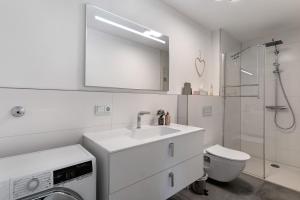 a white bathroom with a sink and a washing machine at Kölsch-Marie in Durbach +16 photos