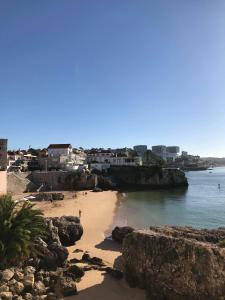 a beach with rocks and the ocean and buildings at Estoril Sea You in Estoril