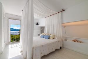 a white bedroom with a canopy bed with a window at Casa Arola in Sant Josep de sa Talaia +32 photos