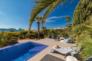 a dog laying on a chair next to a swimming pool at Casa Arola in Sant Josep de sa Talaia