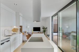 a kitchen with white cabinets and a living room at Suitme-Agaete in Agaete
