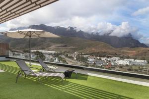 two chairs and an umbrella on a balcony with mountains at Suitme-Agaete in Agaete