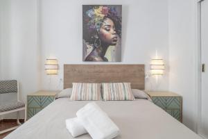 a bedroom with a bed with a painting on the wall at Apartamento Playa Regla in Chipiona