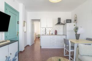 a kitchen with white cabinets and a table and a refrigerator at Apartamento Playa Regla in Chipiona