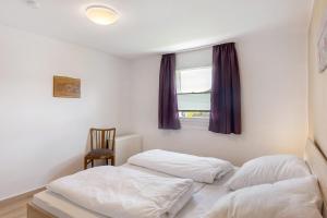 two beds in a room with a window and a chair at Ferienhaus Grobbel in Eslohe