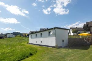 a white house on a grassy hill with an umbrella at Ferienhaus Grobbel in Eslohe