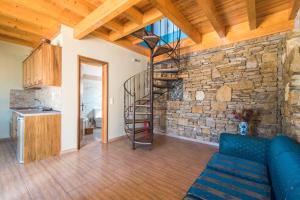 a living room with a stone wall and a spiral staircase at Mirage Arillas Maisonette B in Arillas
