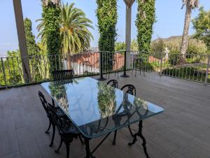 a glass table and chairs on a balcony with palm trees at Bastion del Drago in Arucas