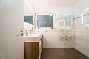 a white bathroom with a sink and a mirror at Sonnenterrasse 9 in Fischerbach +33 photos