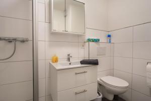 a white bathroom with a toilet and a sink at Ferienwohnung Ausblick in Bremerhaven +26 photos