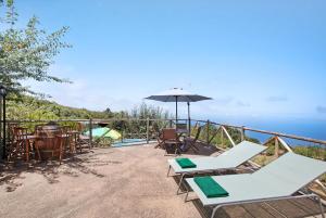 a patio with chairs and tables and an umbrella at Finca Las Carmenes in Icod de los Vinos