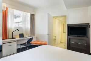 a hotel room with a bed and a desk and a tv at ibis Wellington in Wellington