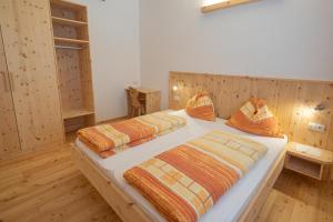 two beds in a room with wooden walls and wooden floors at Apartment Enzian - Mesnerhof in Sand in Taufers