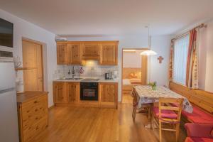 a kitchen with wooden cabinets and a table with a dining room at Apartment Enzian - Mesnerhof in Sand in Taufers