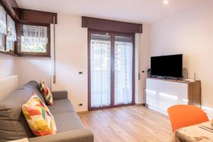 a living room with a couch and a flat screen tv at Casa Muffolina in Canazei