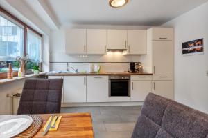 a kitchen with white cabinets and a table and chairs at Ferienwohnung Sägegasse, Typ A in Münstertal