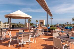 a patio at a hotel with tables and chairs at Cefalù Seaside Pool Villa in Cefalù