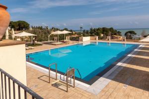 a large blue swimming pool with chairs and umbrellas at Cefalù Seaside Pool Villa in Cefalù