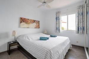 a white bedroom with a bed with blue pillows on it at Casa Sydhavshytten in Nerja +17 photos
