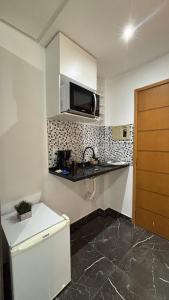 a small kitchen with a sink and a microwave at Lindo Flat Completo 311 in Nova Iguaçu