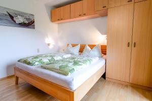 a bedroom with a bed with white sheets and wooden cabinets at Heizmannshof in Hofstetten