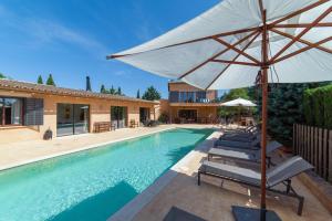 a pool with chairs and an umbrella next to a house at S'hort des Frares in El Palmer