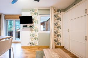 a living room with a tv and a sliding door at Studio Bee Happy in Brides-les-Bains