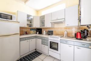 a white kitchen with white cabinets and appliances at Aux Pins Maritimes - A22 in Pornic