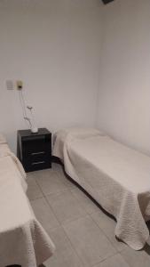 a bedroom with two beds and a night stand with a lamp at Alojamiento El Centenario in San Martín
