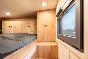 a bedroom in a tiny house with a large window at Tiny House Ingo John 'Vanessa' in Sandstedt
