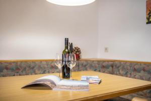 a table with a bottle of wine and a book at Manuel's App Watschinger - Frieda in Sesto