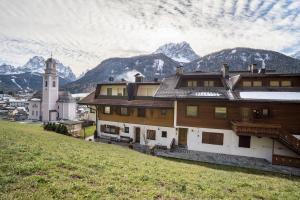 a building on a hill with a clock tower and mountains at Manuel's App Watschinger - Frieda in Sesto