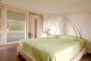 a bedroom with a bed with a green comforter at Villa delle Palme in Cecina