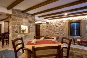 a dining room with a table and chairs and a stone wall at Arcaloro Resort in SantʼAngelo di Brolo