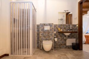 a bathroom with a toilet and a tile wall at Arcaloro Resort in SantʼAngelo di Brolo +19 photos