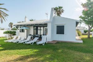 a group of white chairs sitting on a lawn at Casa 3 O en Complejo Binisafua in Binisafua