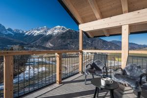 a deck with chairs and a table and mountains at Arnica Alpin Lodge in Cavedago