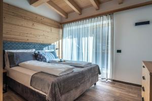 a bedroom with a bed and a large window at Arnica Alpin Lodge in Cavedago