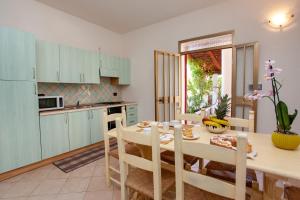 a kitchen with a table and a dining room with blue cabinets at Casa delle Mimose in Orosei +23 photos