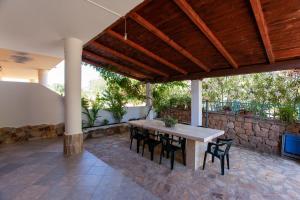 a patio with a table and chairs under a wooden roof at Casa delle Mimose in Orosei
