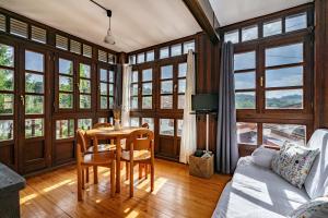 a living room with a table and chairs and windows at Casa Florenta G2 in Cangas de Onís