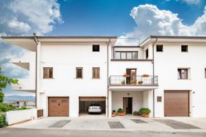 a white house with a car parked in the driveway at Dolcecasa in Dorgali