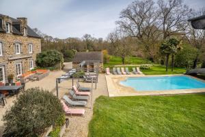 a backyard with a pool and chairs and a house at Gîte Les Hervelines in Pleudihen-sur-Rance