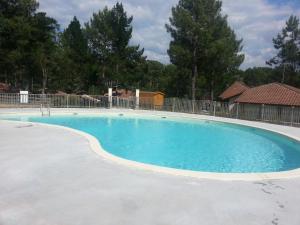 a large swimming pool with blue water at Maison, Piscine sous les pins in Moliets-et-Maa