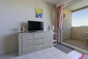 a living room with a television on a dresser at Appartement clim piscine garage in Le Grau-du-Roi